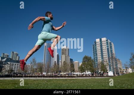 Pieds de coureur sportif dans le parc de la ville. Concept de jogging à l'extérieur. Homme en train de courir pour faire de l'exercice sur fond de ville. Banque D'Images