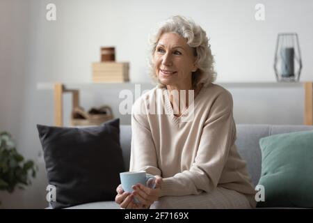 Femme mûre et pensive souriante tenant une tasse de thé ou de café Banque D'Images