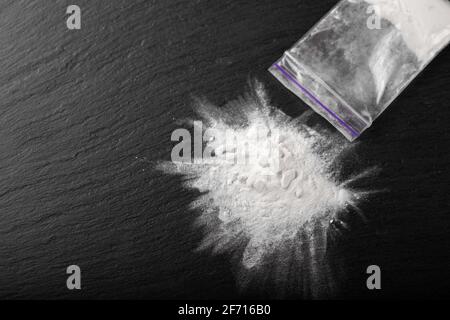 Cocaïne dans un emballage plastique sur fond noir, gros plan. Médicaments interdits. Banque D'Images