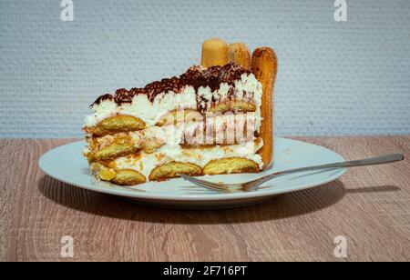 Morceau de gâteau Tiramisu avec des ladyfingers, de la crème fouettée et de la poudre de chocolat sur une assiette Banque D'Images