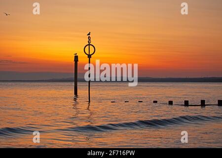 Portobello, Édimbourg, Écosse, météo britannique. 4 avril 2021. Magnifique lever du soleil le dimanche de Pâques au bord de la mer, température 5 degrés centigrade. Trois oiseaux de mouettes inclus dans ce tir, y compris le nouveau numéro sur le poteau qui a été ajouté la semaine dernière pour aider les services d'urgence à localiser l'emplacement correct si on l'appelle à la plage. Banque D'Images