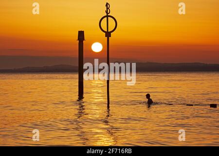 Portobello, Édimbourg, Écosse, météo britannique. 4 avril 2021. Magnifique lever du soleil le dimanche de Pâques au bord de la mer, température 5 degrés centigrade. Nageur d'eau froide dans le Firth of Forth à côté de la plage groyne. Banque D'Images