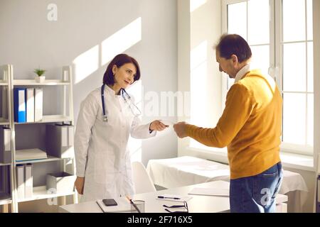 Un médecin féminin souriant amical donne une ordonnance ou une recommandation à un patient mâle mature. Banque D'Images