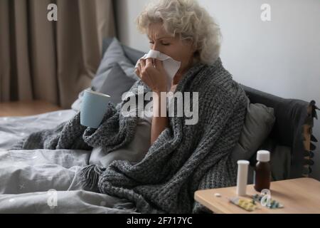 Femme âgée malade frustrée couverte d'une couverture chaude Banque D'Images