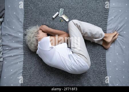 Calme femme âgée dormant dans la pose foetale après avoir pris des médicaments Banque D'Images
