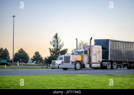 Deux semi-camions classiques American Idol avec des semi-remorques brillantes pièces chromées, tuyaux d'échappement verticaux élevés et fourgonnette sèche semi-remorques debout sur le parki Banque D'Images