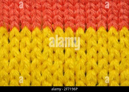 Tissu synthétique en maille jaune et rouge gros plan. Texture tricotée. Texture tricotée à motifs multicolores. Arrière-plan Banque D'Images