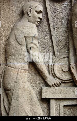 Sculpture art déco d'un ouvrier du métal sur une machine à meuler. La sculpture est sur la rue face à un trottoir public sur un bâtiment à Mumbai (anciennement Banque D'Images