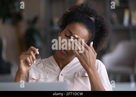 La femme biraciale fatiguée souffre de maux de tête sur le lieu de travail Banque D'Images