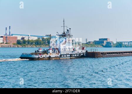 le pousseur pousse la barge de cargaison sèche en vrac sur la rivière dans un paysage industriel Banque D'Images