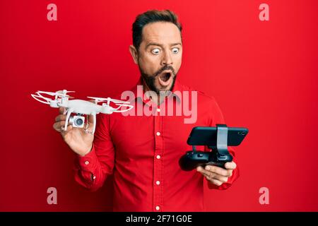 Homme d'âge moyen utilisant un drone peur et choqué avec la surprise et l'expression stupéfaite, la peur et le visage excité. Banque D'Images