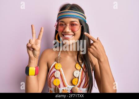 Belle femme hispanique portant le style bohème et hippie faisant la paix symbole sourire heureux pointant avec la main et le doigt Banque D'Images