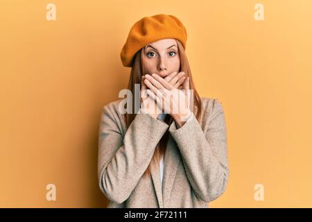 Jeune femme irlandaise portant le regard français avec le béret choqué couvrant la bouche avec les mains pour erreur. Concept secret. Banque D'Images