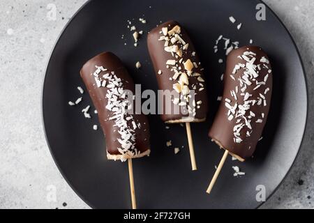 Bananes enrobées de chocolat surgelé avec garnitures sur bâton Banque D'Images