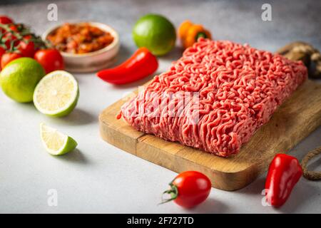 La viande hachée sur la planche à découper est crue avec des ingrédients pour la cuisson sur fond blanc Banque D'Images