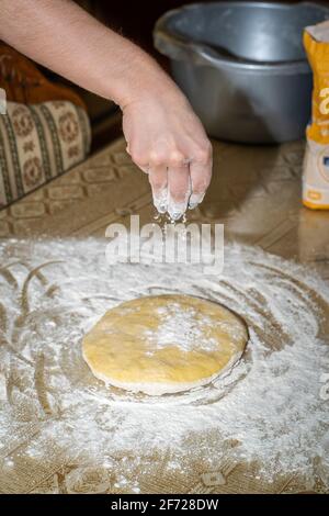 Arrosez à la main la farine sur la pâte à gâteau Banque D'Images