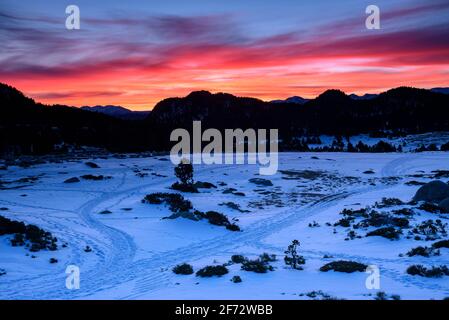 Lever de soleil rouge hivernal au lac Bouillouses. En arrière-plan, le massif des Canigó (Cerdagne, Pyrénées Orientales, Occitanie, France) Banque D'Images