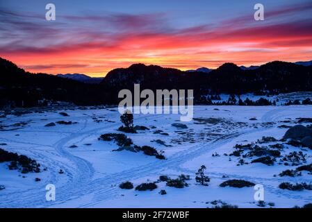 Lever de soleil rouge hivernal au lac Bouillouses. En arrière-plan, le massif des Canigó (Cerdagne, Pyrénées Orientales, Occitanie, France) Banque D'Images