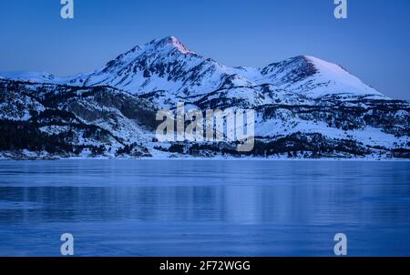 Lever de soleil en hiver au lac Bouillouses. En arrière-plan, pics périques (Cerdagne, Pyrénées Orientales, Occitanie, France) Banque D'Images