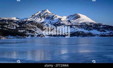 Lever de soleil en hiver au lac Bouillouses. En arrière-plan, pics périques (Cerdagne, Pyrénées Orientales, Occitanie, France) Banque D'Images