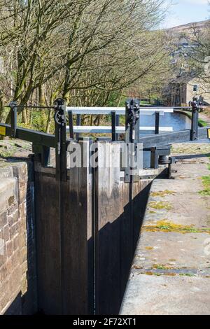 Vue ensoleillée du ressort des portes de verrouillage et d'une serrure vide Chambre sur le canal historique Huddersfield Narrow à Marsden In West Yorkshire Banque D'Images