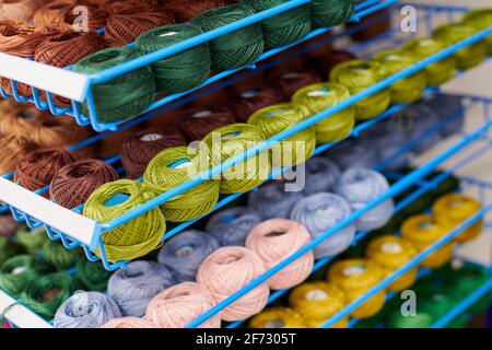 Des fils ou des balles de laine sur les étagères en magasin pour le tricotage et la couture. Accessoires pour la mercerie dans les étagères des magasins de tissus. Image multicolore, ba Banque D'Images