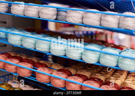 Des fils ou des balles de laine sur les étagères en magasin pour le tricotage et la couture. Accessoires pour la mercerie dans les étagères des magasins de tissus. Image multicolore, ba Banque D'Images