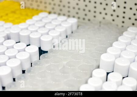 Pots cylindriques en plastique avec bouchons ronds pour suppléments ou produits alimentaires. Récipients blancs opaques en matières premières sur étagère pour l'industrie pharmaceutique. Prêt t Banque D'Images