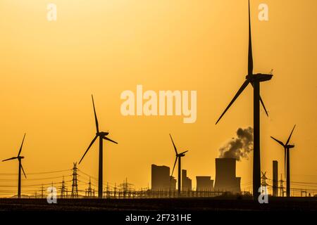 Éoliennes et pylônes de puissance au coucher du soleil devant la centrale électrique au lignite Niederaussem de RWE Power AG, Niederaussem, Nord Banque D'Images