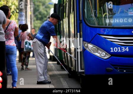 salvador, bahia / brésil - 8 juillet 2016: Homme âgé à mobilité réduite prenant un bus à un arrêt sur l'Avenida Tancredo Neves dans la ville de Salvado Banque D'Images