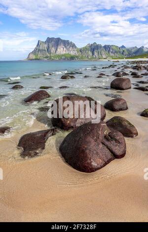 Côte et montagnes, grandes pierres sur la plage de sable d'Uttakleiv, Lofoten, Nordland, Norvège Banque D'Images