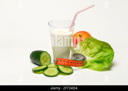 Verre de babeurre, concombre, feuille de laitue et pomme, lait, paille, laitue, laitue, concombre, ruban de mesure Banque D'Images