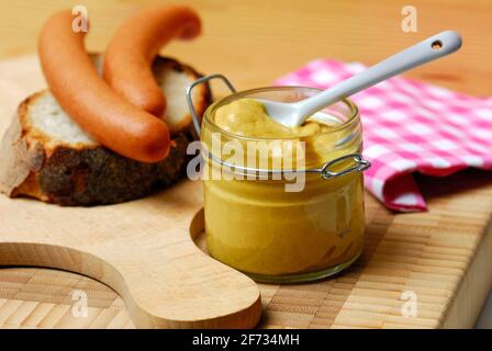 Pot à moutarde, moutarde, saucisses sur pain, saucisses de Vienne, planche à découper, épice Banque D'Images