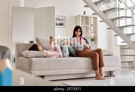 Mère de famille indienne avec fille adolescente utilisant des téléphones à la maison. Banque D'Images