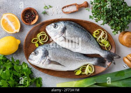 Deux poissons dorado non cuits et ingrédients pour le poisson grillé, vue du dessus. Cuisine de la mer Dorado, nourriture saine Banque D'Images