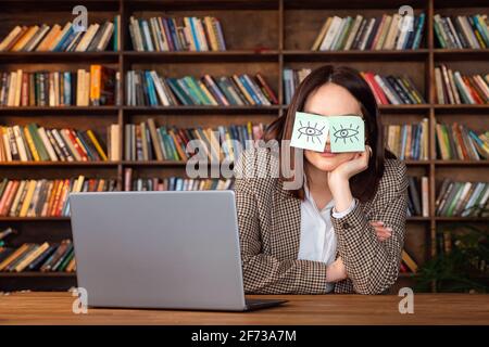 Un travailleur de bureau paresseux drôle qui se couche sur le lieu de travail pour couvrir les yeux avec des notes collantes. Concept de tricherie au sommeil Banque D'Images