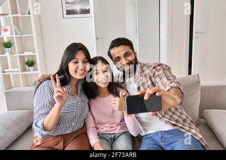 Bonne famille indienne drôle avec fille de l'adolescence prenant selfie sur le téléphone à la maison. Banque D'Images