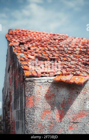 Vue de près verticale d'une maison non finie avec un toit en tuiles de triangle recouvert d'argile rougeâtre partiellement désordonné et mur de briques avec Banque D'Images