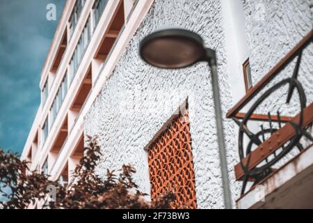 Vue sur une façade de maison avec un accent sélectif sur un mur blanc à texture grossière et plastré avec une grille de fenêtre en argile; un lampadaire et une partie d'un balcon Banque D'Images
