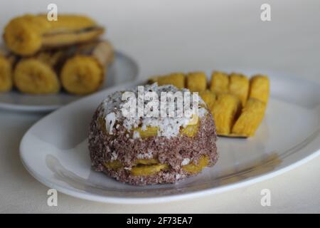 Gâteau de farine de millet à la vapeur avec une généreuse couche de noix de coco fraîche entre les deux. Connu localement sous le nom de Ragi puttu. Servi avec du plantain à la vapeur. Prise de vue activée Banque D'Images