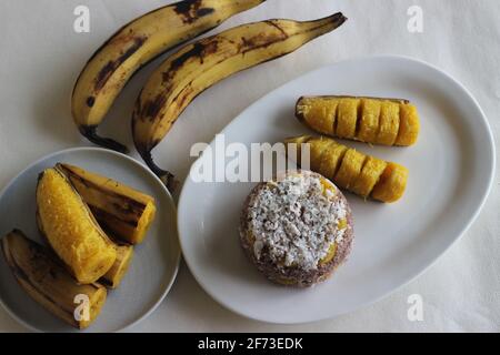 Gâteau de farine de millet à la vapeur avec une généreuse couche de noix de coco fraîche entre les deux. Connu localement sous le nom de Ragi puttu. Servi avec du plantain à la vapeur. Prise de vue activée Banque D'Images