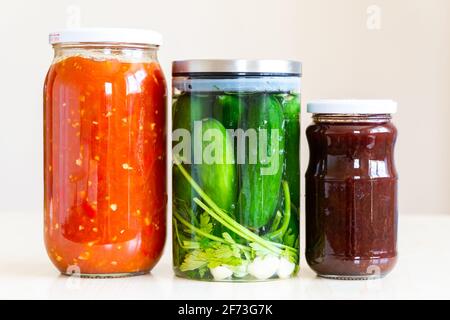 pots en verre remplis de sauce tomate, concombres marinés et confiture Banque D'Images