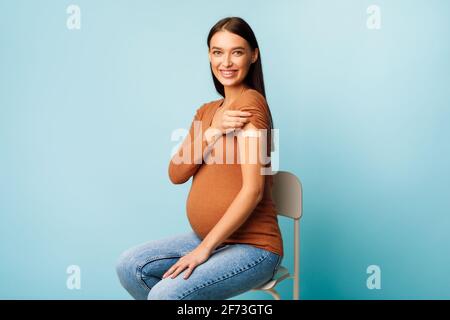 Femme enceinte vaccinée contre Covid-19 montrant le bras avec bandage, Studio Banque D'Images