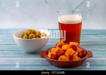 Concept de gastronomie espagnole. Assiette en argile avec pommes de terre frites avec une sauce épicée appelée en Espagne 'Patatas Bravas' avec un bol blanc d'oliviv farci Banque D'Images