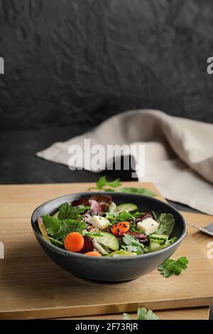 Bol de salade fraîche avec légumes sur fond sombre Banque D'Images