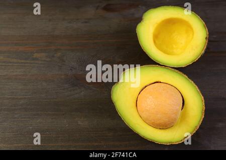 Gros plan de moitié d'avocat mûr frais isolé sur brun foncé arrière-plan en bois Banque D'Images