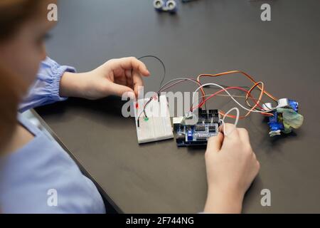 Gros plan à angle élevé d'enfants expérimentant avec des circuits électriques tout en construisant des robots pendant la classe d'ingénierie dans l'école de développement Banque D'Images