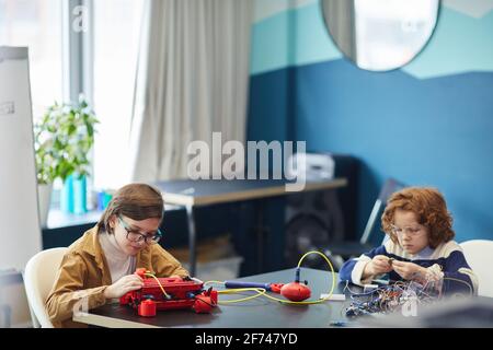 Portrait grand angle de deux garçons construisant des robots tout en appréciant la classe d'ingénierie dans l'école de développement, l'espace de copie Banque D'Images