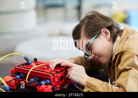 Vue latérale portrait d'un joli garçon construisant une machine robotique pendant cours d'ingénierie à l'école de développement Banque D'Images