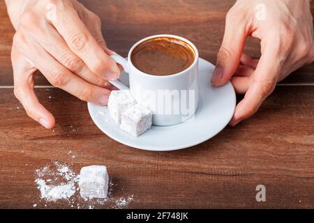 Une femme turque de race blanche boit du café turc traditionnel dans une tasse spéciale. Le café est servi avec un délice turc sur le côté de l'assiette Banque D'Images
